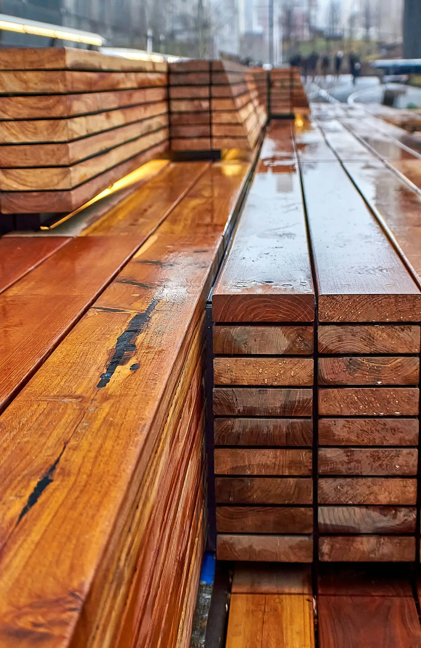 Stacked hardwood decking boards wet with rain
