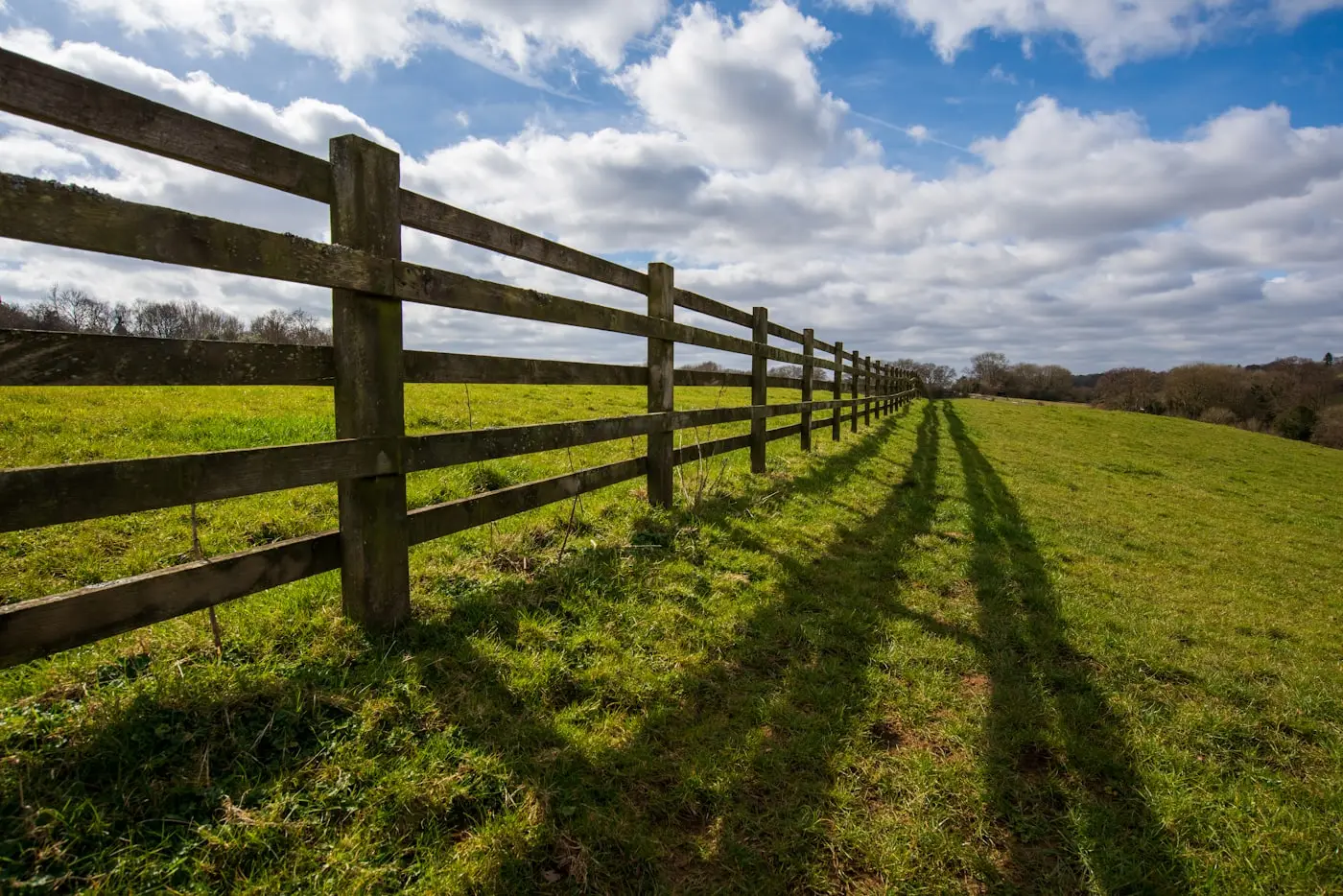 Post and rail fence running across a green field