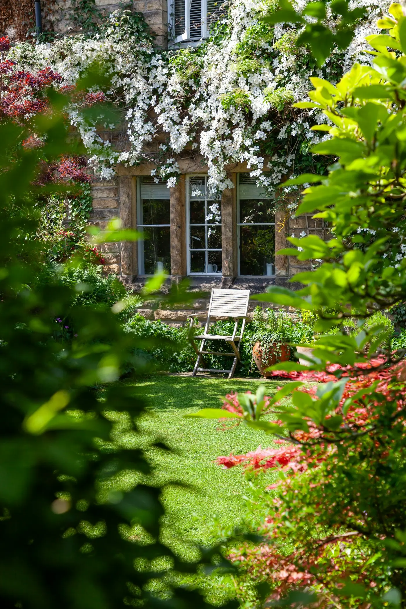 Stone house with bench and planted borders